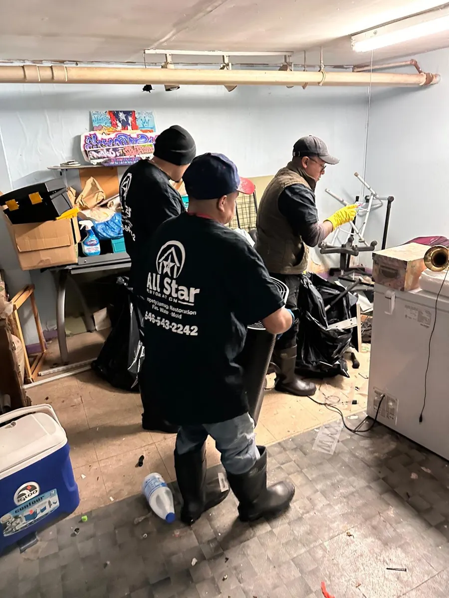 All Star Restoration crew in gloves and boots removing contaminated contents from a Brooklyn basement after a sewage backup