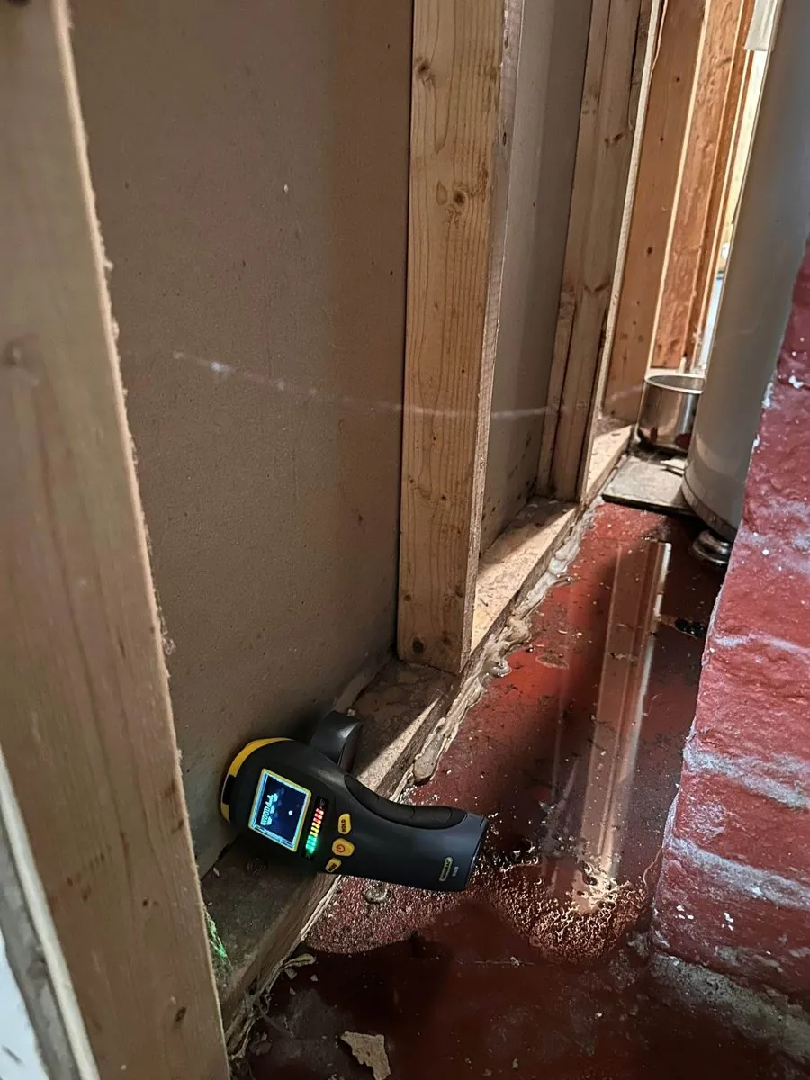 Moisture meter at the bottom of an opened basement wall