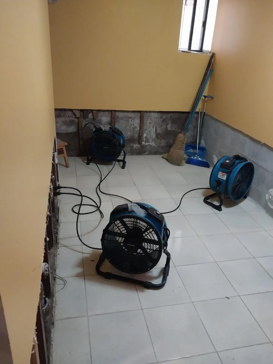 Air movers drying a basement room with the lower walls opened up after a water heater leak in Marine Park, Brooklyn