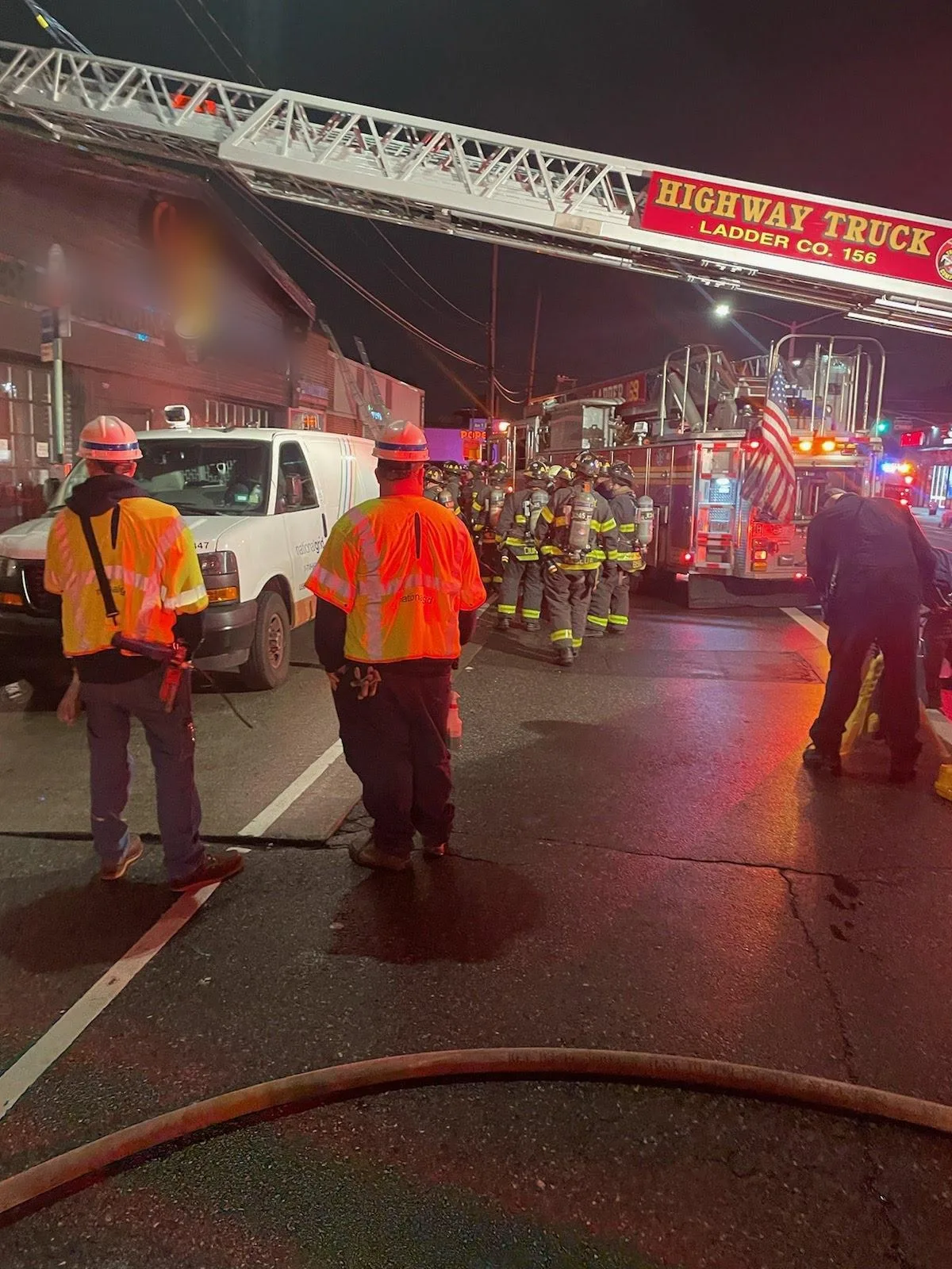 FDNY ladder truck and firefighters outside a commercial building fire at night in Brooklyn