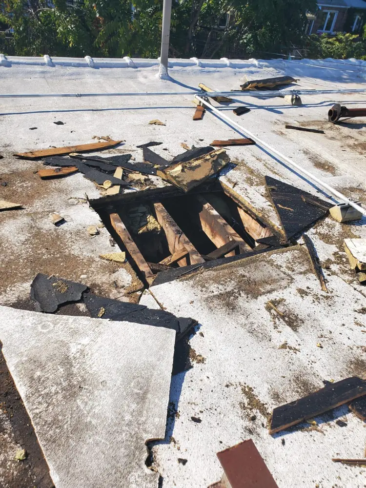Fire-damaged flat roof with an opening exposing charred wood joists